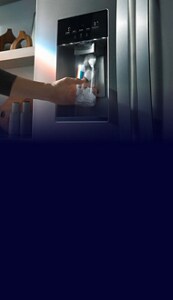 Hand filling a glass of water from a stainless steel refrigerator dispenser